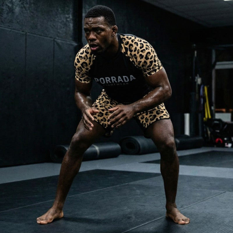 Male grappling athlete wearing Porrada Fightwear leopard BJJ rash guard and shorts while training in a martial arts gym.